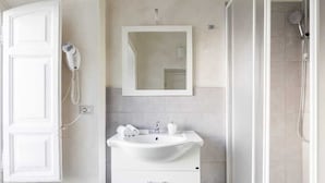 A bathroom with a white sink, mirror, and shower. - Urbana collection guest house (Rome)