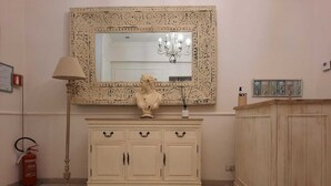 A room with a cream-colored cabinet, a large ornate mirror, a statue, a floor lamp, and a fire extinguisher. - Urbana collection guest house (Rome)