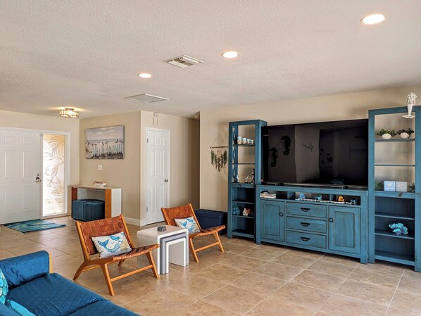 A living room with a sofa, chairs, a TV, and a cabinet.
