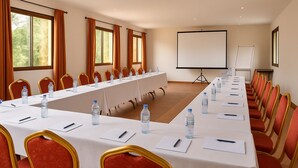 A conference room with a long table, red chairs, water bottles, and a projector screen. - La Résidence Therésia LRT (Lomé)