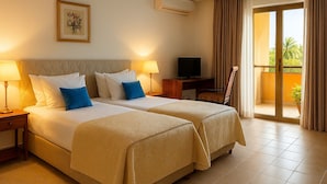 A hotel room with two beds, a television, an air conditioning unit, and a balcony with curtains. - La Résidence Therésia LRT (Lomé)