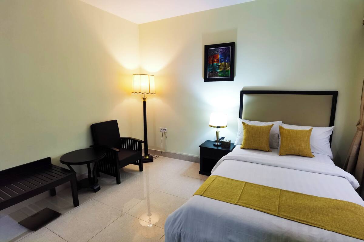 Une chambre d’hôtel avec un lit, un banc, une table et une lampe.