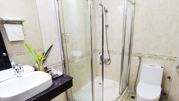 A bathroom with a glass-enclosed shower, a white sink, and a toilet. - Milan Hotel By JK6 (Phnom Penh)