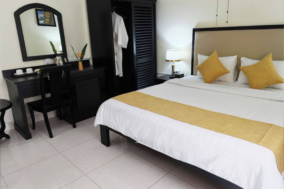 Une chambre d’hôtel comprenant un lit, une table de chevet, une lampe et un bureau avec une chaise.