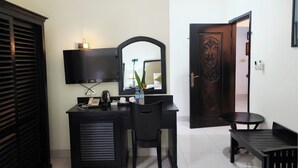 Een hotelkamer met een bureau, stoel, televisie en een decoratieve deur.