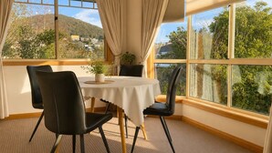 Un comedor con una mesa, sillas y vistas a una montaña y árboles.