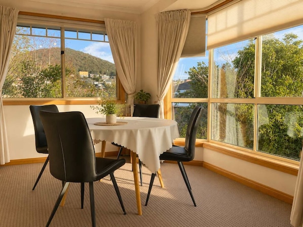 A dining area with a table, chairs, and a view of a mountain and trees.