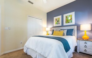 Quarto com cama, abajures, mesa de cabeceira e duas obras de arte emolduradas na parede.