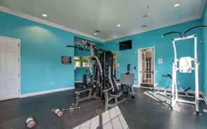 A gym with various exercise equipment, a mirror, and a sign on the wall. - South-Facing Splash Pool • Resort Amenities • Gated • 7 Miles to Disney (Kissimmee)