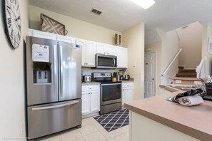 A modern kitchen with stainless steel appliances, white cabinetry, and a microwave.