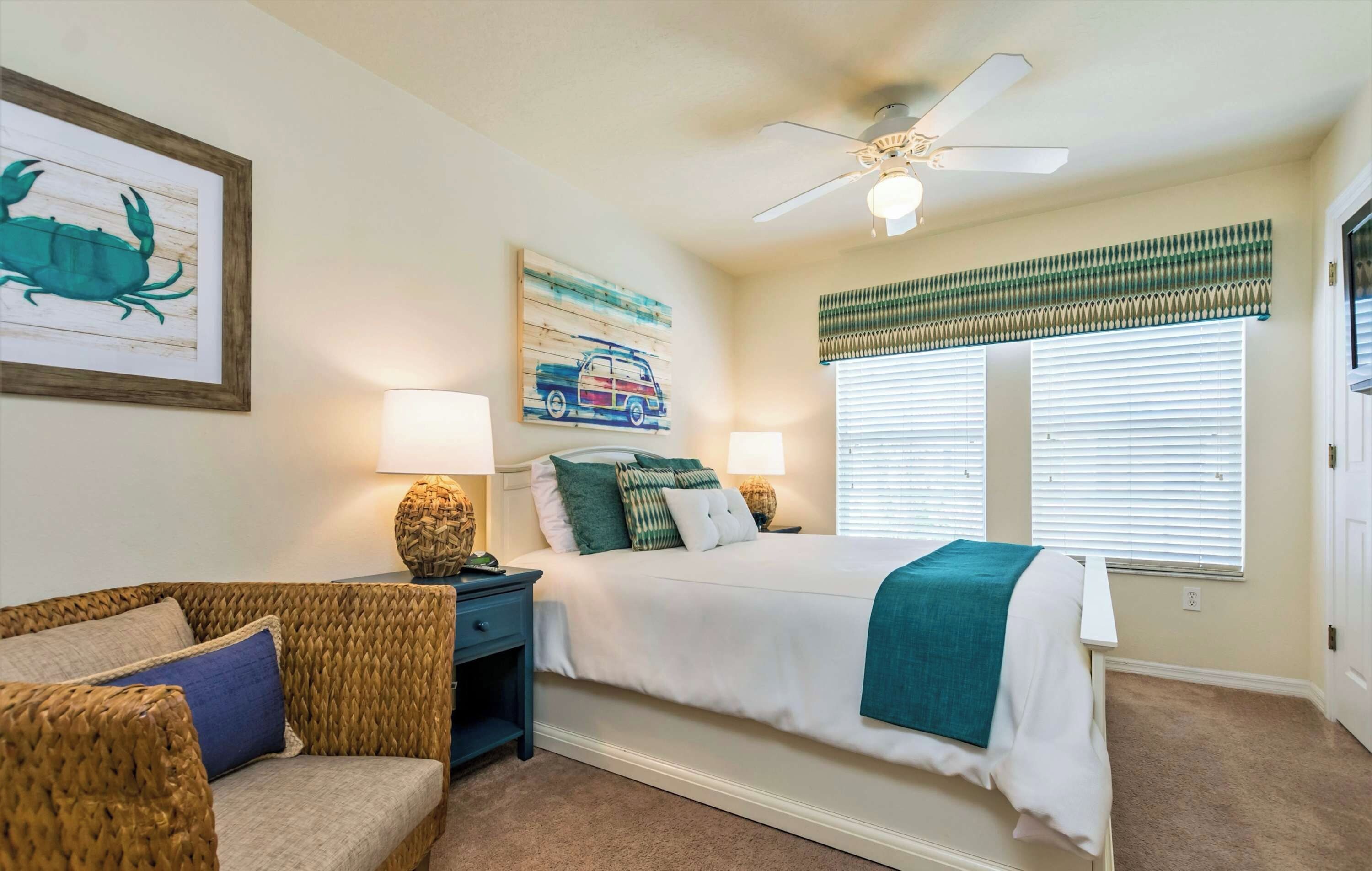 A bedroom with a bed, nightstands, a chair, a ceiling fan, and artwork on the walls.