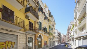 A narrow street with multi-story buildings, balconies, and a parked car. - GuestHost - Comfortable 64 sqm apartment, able to accommodate up to 4 people, located on the ground floor of a building.The property is located in a semi-central area of ​​Bari, well served and well connected to the main points of interest of the cit (Bari)