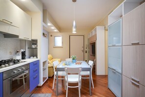 A compact kitchen with a dining area, a stove, and a refrigerator.