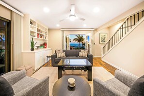 Una sala de estar con sofá, mesa de centro y estantería.