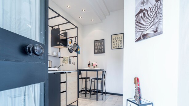 A modern kitchen with black cabinetry, a dining area with two chairs, and a small table. - Casa Gioia (Lucca)