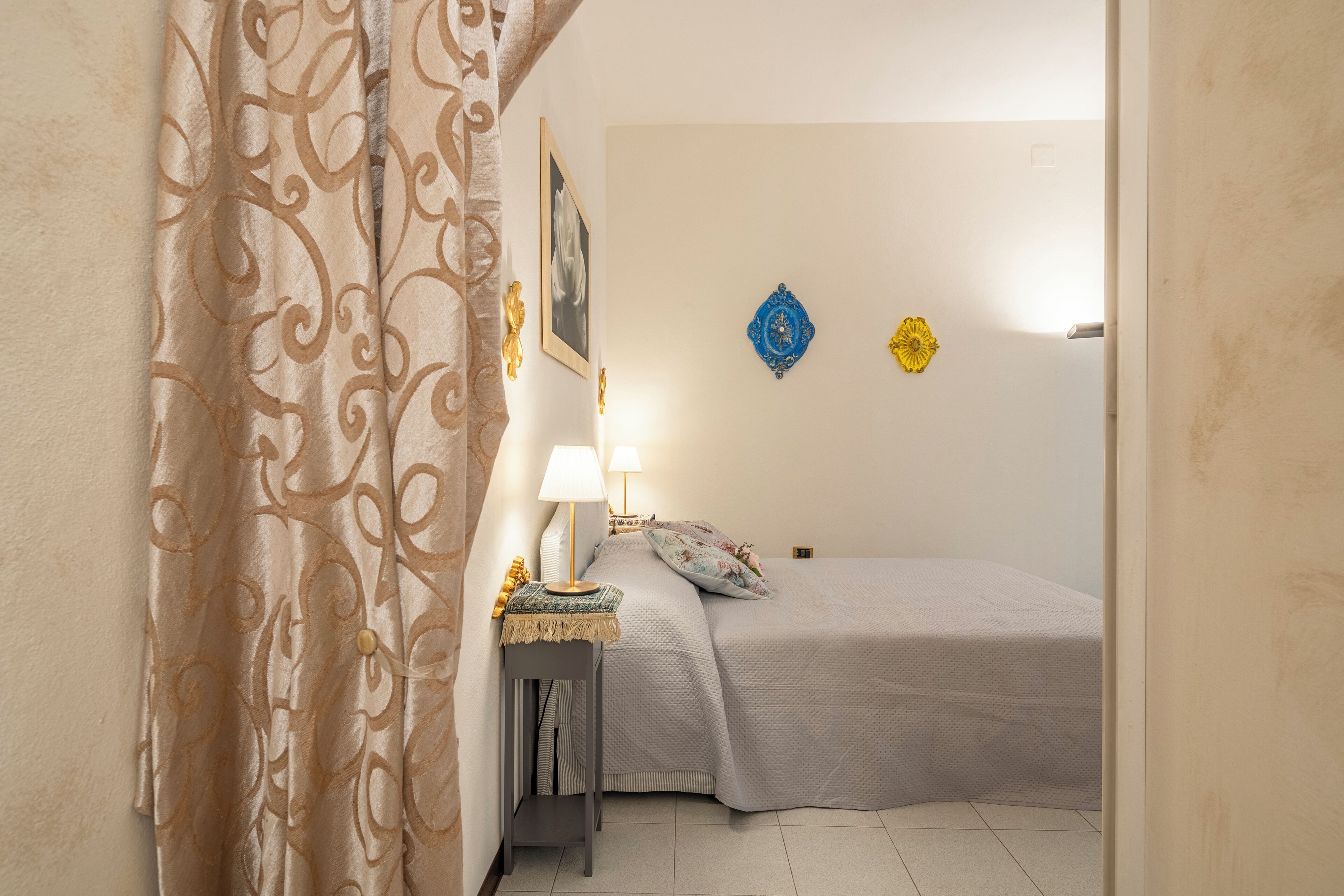 A bedroom with a bed, bedside tables, a lamp, and decorative wall art.