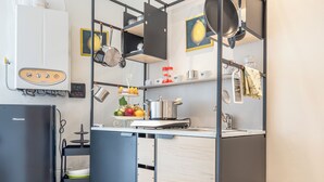 A modern kitchen with a Hisense refrigerator, a stove, and a sink. There are pots and pans hanging above the stove, and a fruit bowl on the counter. - Casa Gioia (Lucca)