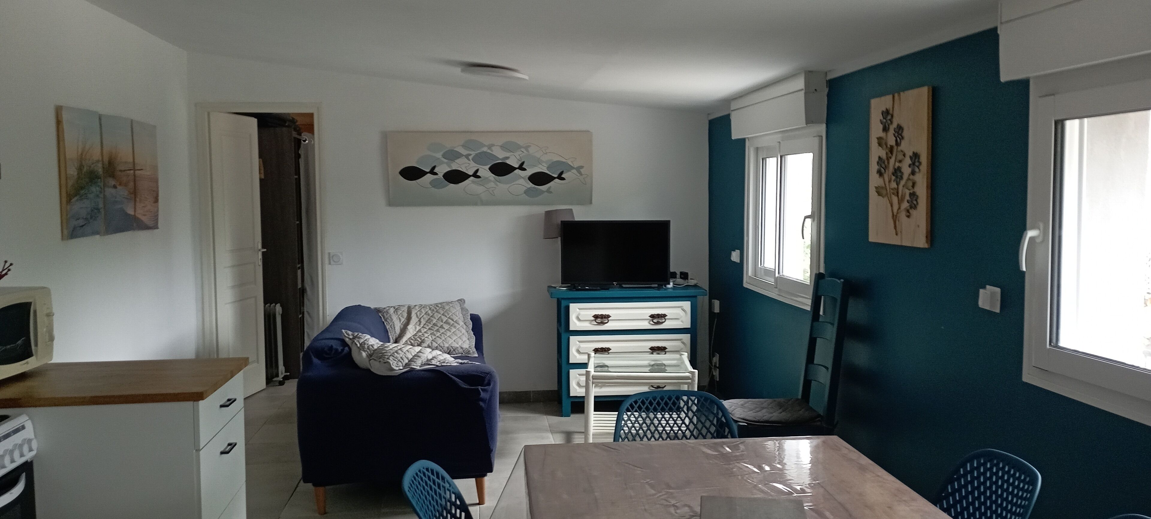 En kompakt opholdsstue med sofa, spisebord, fjernsyn og et vindue.