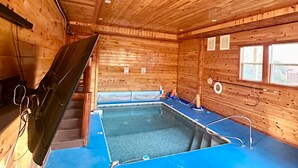 A wooden cabin interior with a pool area, including a diving board and a slide.