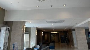 A spacious lobby with a modern chandelier, seating area, and a reception desk.