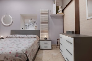 Ein Schlafzimmer mit Bett, Nachttisch, Kommode, Spiegel und einer eingebauten Ablage mit Dekoration.