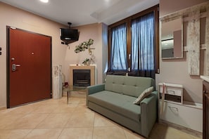 Ein Wohnzimmer mit einer Couch, einem Fernseher, einem Kamin und einer Tür.