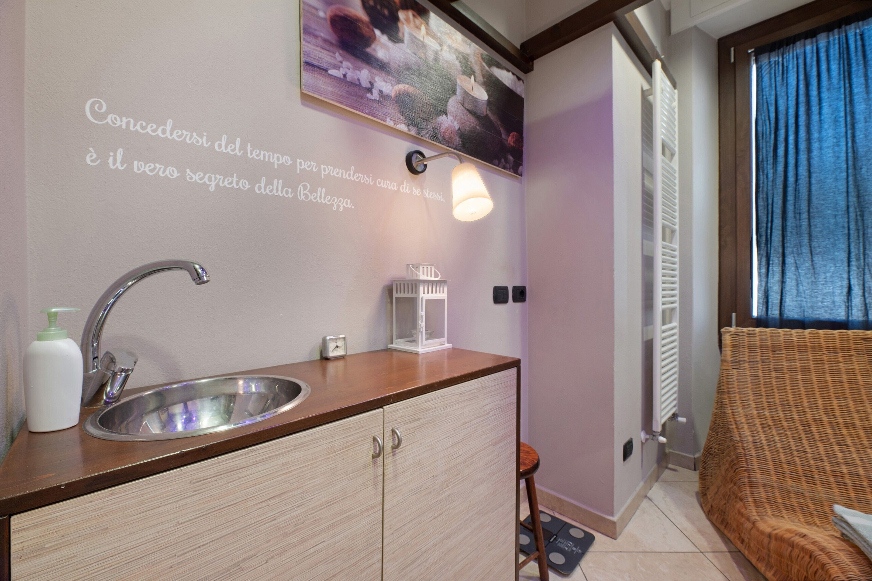 A bathroom with a sink, a mirror, a towel, and a wall-mounted light fixture.