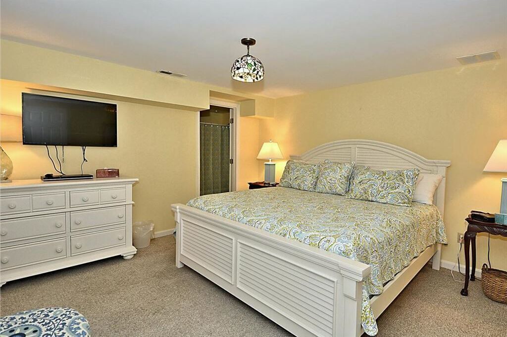 A bedroom with a bed, a dresser, a television, and a lamp.