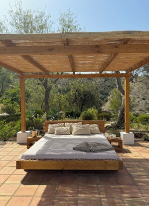 A wooden bed with a canopy in a garden setting. - Near the Caminito del Rey, Malaga, Marbella and Ronda, hiking and pool (Pizarra)
