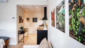 Un salon moderne avec un canapé, une table basse et un coin repas doté d’un comptoir de cuisine. Plusieurs œuvres d’art ornent les murs.
