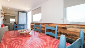 A dining area with a red polka dot tablecloth, blue chairs, and a wooden bench.