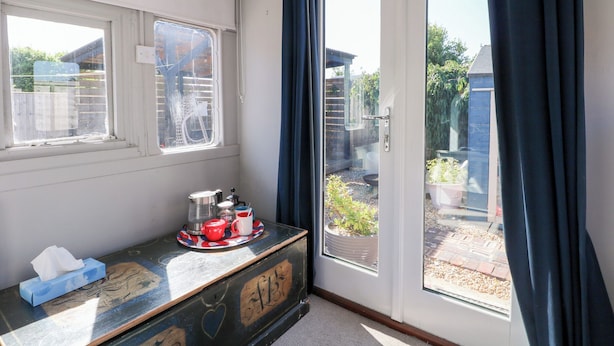 A room with a window, a door, and a small table with a tissue box and a tray with cups and a teapot.