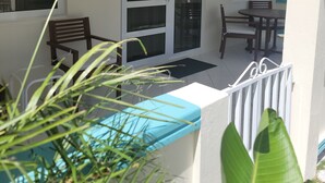 Un área de estar al aire libre techada con ventilador de techo, una flor decorativa en la puerta y vistas del patio.