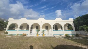 Un edificio con fachada blanca y detalles azules, que presenta varios ventanales en arco y una entrada central.
