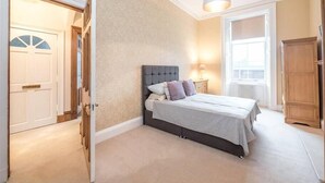 Une chambre à coucher avec un lit, une table de chevet, une lampe et une armoire.