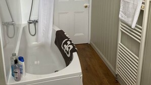 Une salle de bain avec une baignoire, une douche et un porte-serviettes.