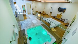 Un baño moderno con una bañera de hidromasaje, ducha con mampara de vidrio y suelo de madera.