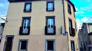 A multi-story building with a beige facade, multiple windows with black frames, and balconies with wrought iron railings. - Chez Armande 2-star tourist apartment 48 m2 (Châtel-Guyon)