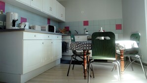 A kitchen with white cabinets, a microwave, a coffee maker, and a table with a polka dot tablecloth. - Chez Armande 2-star tourist apartment 48 m2 (Châtel-Guyon)