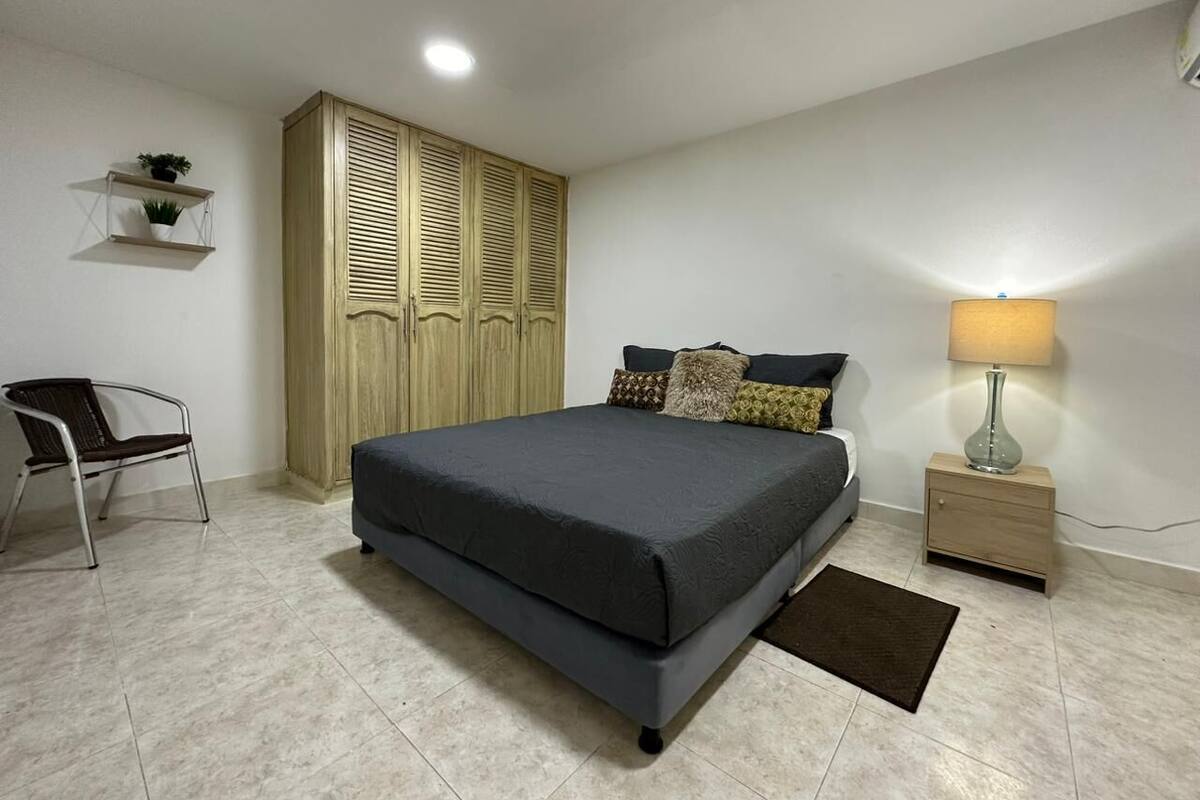 A bedroom with a bed, a nightstand, a chair, and a wardrobe.