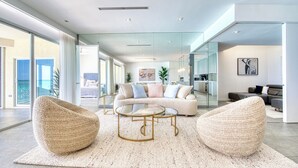A spacious living room with a large sofa, two bean bag chairs, and a coffee table. - Laguna Del Mar - Prime Beachfront Luxury (Grand Cayman)