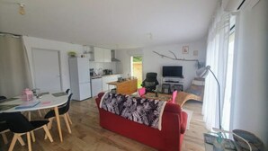 A compact living space with a dining area, kitchenette, and a red sofa. - My little house: out of sight, out of mind (Acquigny)