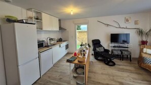 A compact living space with a kitchenette, a dining area, and a seating area with a TV. - My little house: out of sight, out of mind (Acquigny)