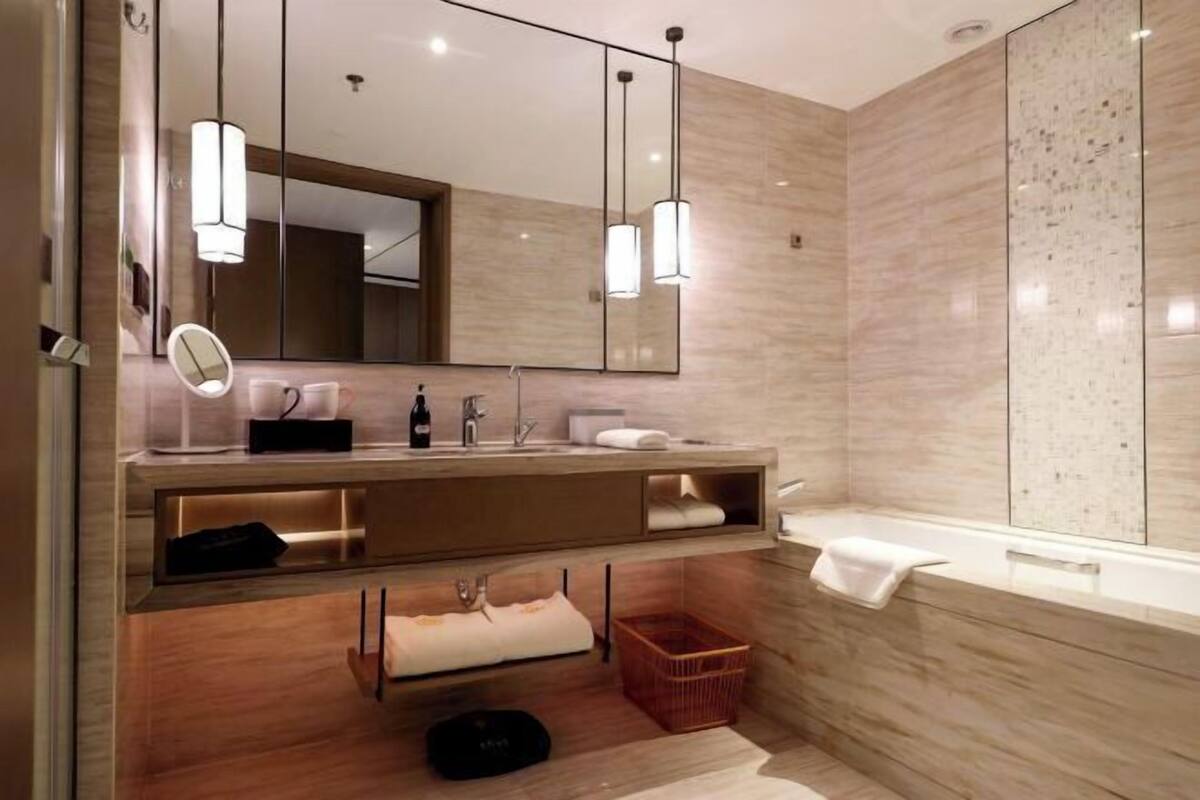 Een moderne badkamer met een houten wastafelmeubel, een grote spiegel en een vrijstaand bad.