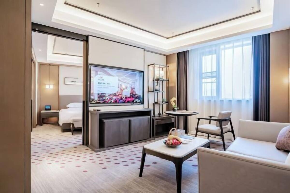 Een hotelkamer met een bed, een televisie, een koffietafeltje en een bank.