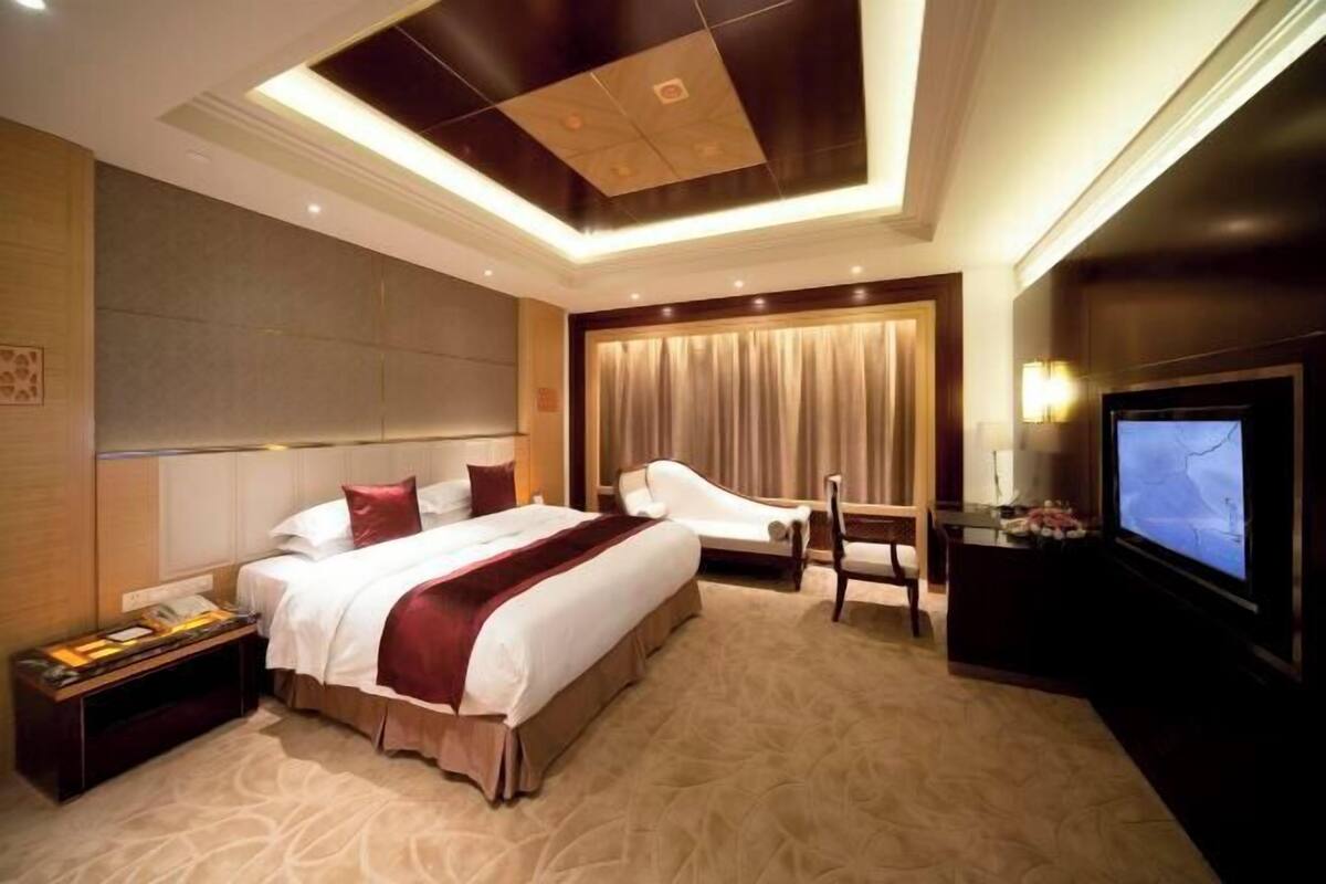 Een hotelkamer met een groot bed, een zithoek met een stoel, een televisie en een bureau.