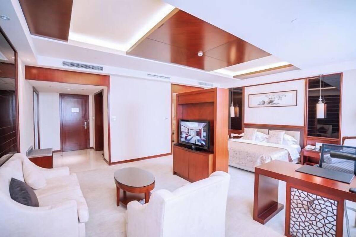 Een hotelkamer met een bed, een televisie, een bureau en een zithoek.