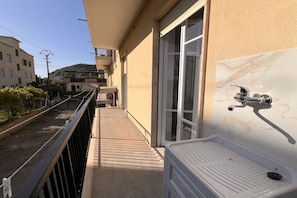A balcony with a white bathtub, a metal railing, and a view of neighboring buildings. - Cozy and modern apartment a stone's throw from the sea (Fuscaldo)