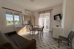 Un espace de vie compact comprenant un coin cuisine, un coin repas et un téléviseur fixé au mur.