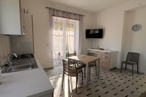 Une cuisine compacte équipée d’un évier, d’une cuisinière et d’un coin repas avec des chaises et une table.